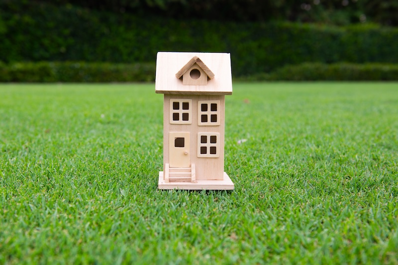 Litet trähus på gräsmatta - symboliserar attefallshus